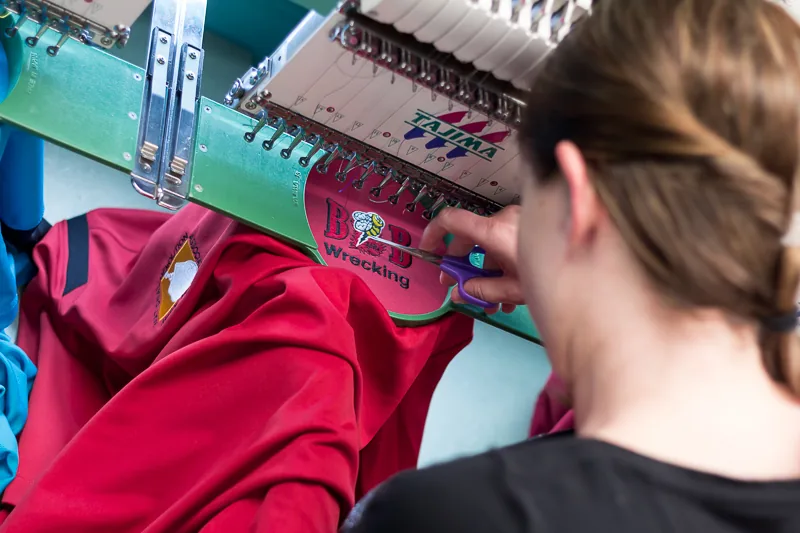 Embroidery machine stitching a logo onto a red jacket
