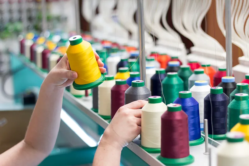Rows of colorful embroidery thread spools on a commercial embroidery machine